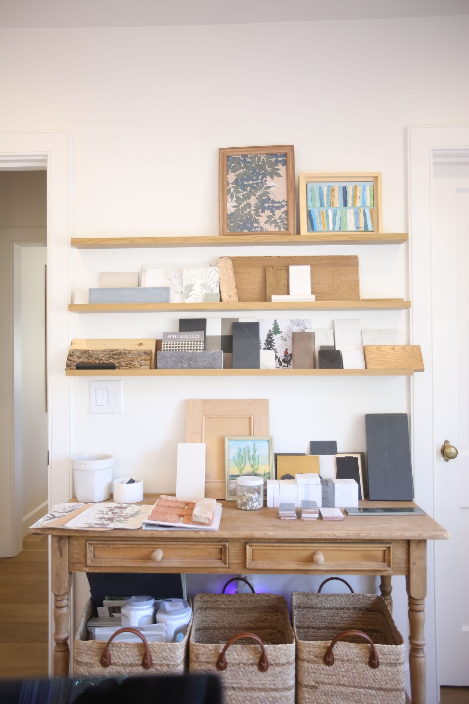 Rustic wooden console table with floating shelves displaying artwork and decor in a minimalist white room setting. Jen Wilbur Photos