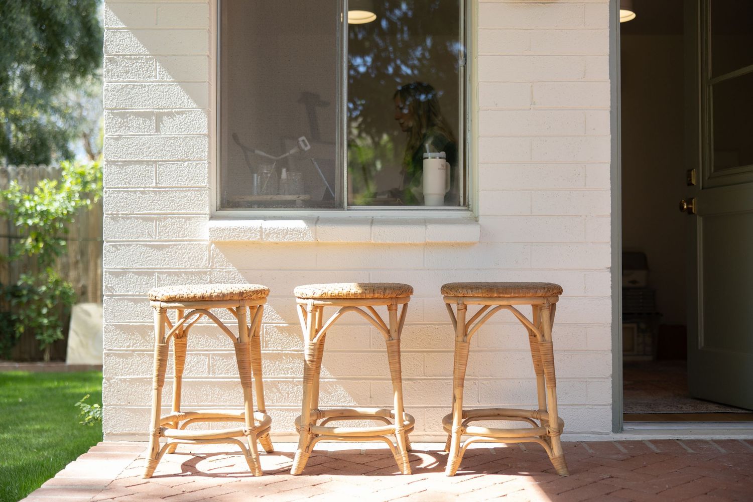 Three rattan chairs sit on a sunny patio against a light beige stucco wall. Jen Wilbur Photos, Scottsdale Photographer