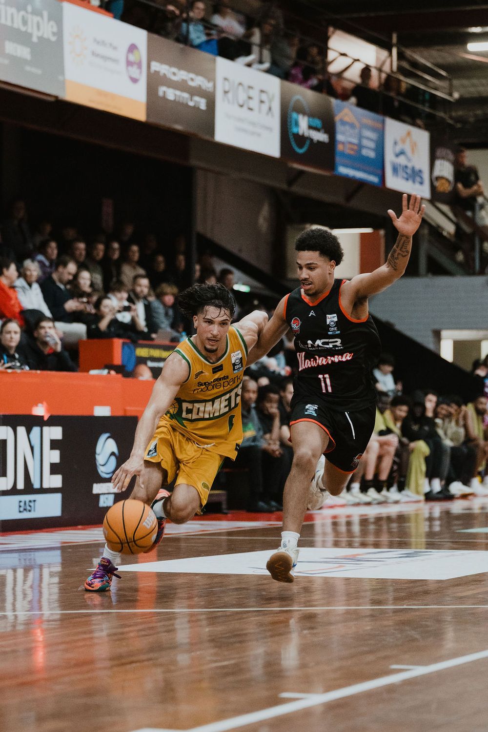 Two basketball players dive for a loose ball during an intense game on a professional court.