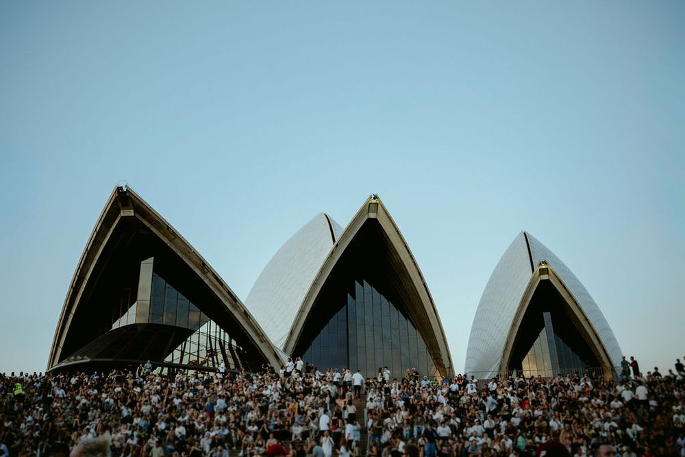 Multiple views of the iconic Sydney Opera House sails against a blue sky.