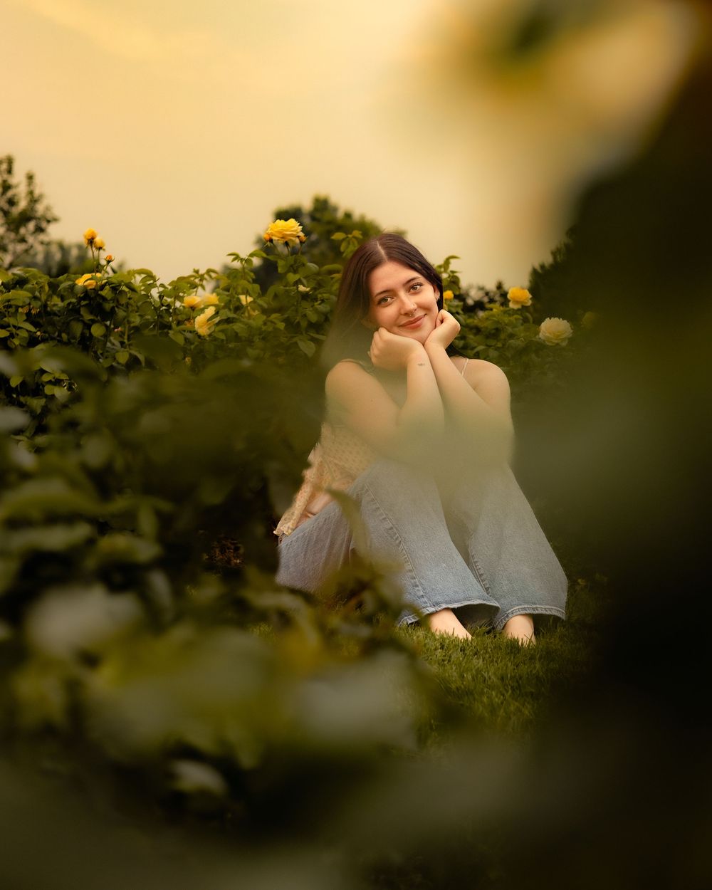A warm candid shot through leaves captures a couple sitting together in golden afternoon sunlight.