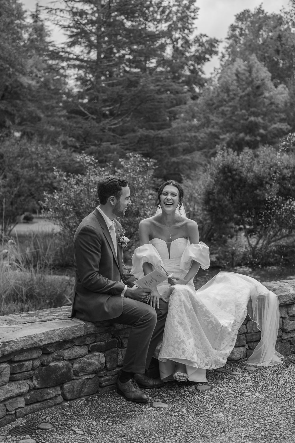 A couple in wedding attire sits together on a stone wall in a garden setting, shown in a series of candid moments.
