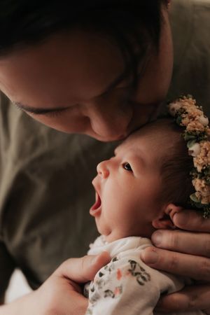 A tender moment between parent and baby showing gentle affection in a soft, intimate lighting setting在柔和溫馨的燈光下，父母和嬰兒之間流露出溫柔的愛意。