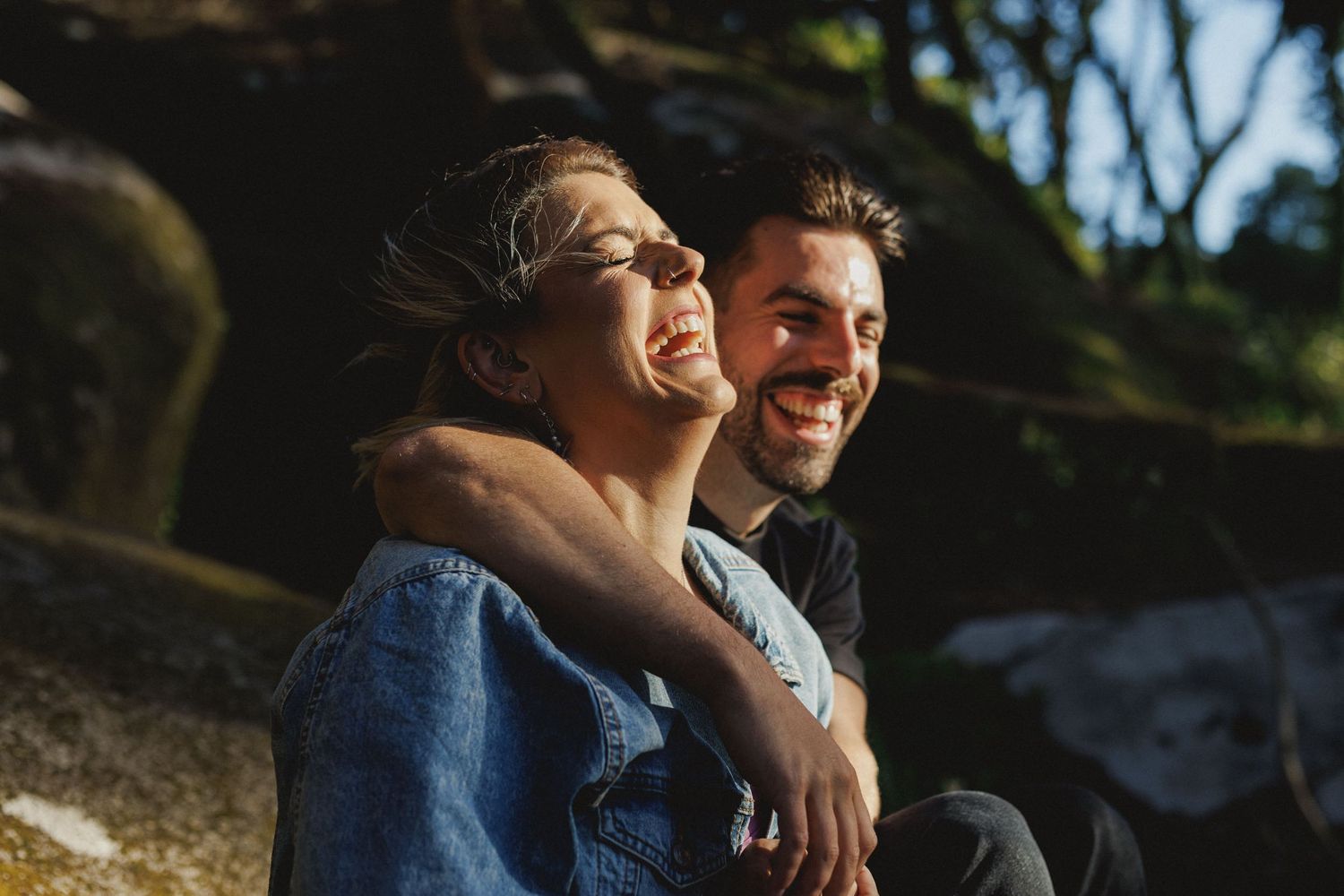 Close-up of happy couple laughing in warm sunlight during pre-wedding photoshoot in Sintra forest, Portugal