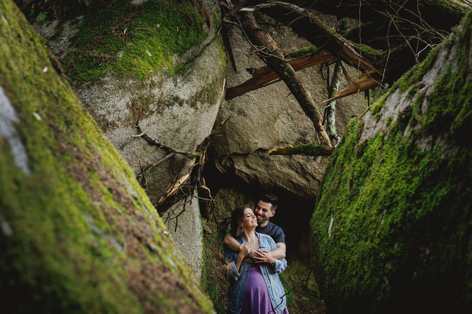 Intimate couple embracing between rocks in forest during pre-wedding photoshoot in Sintra, Portugal