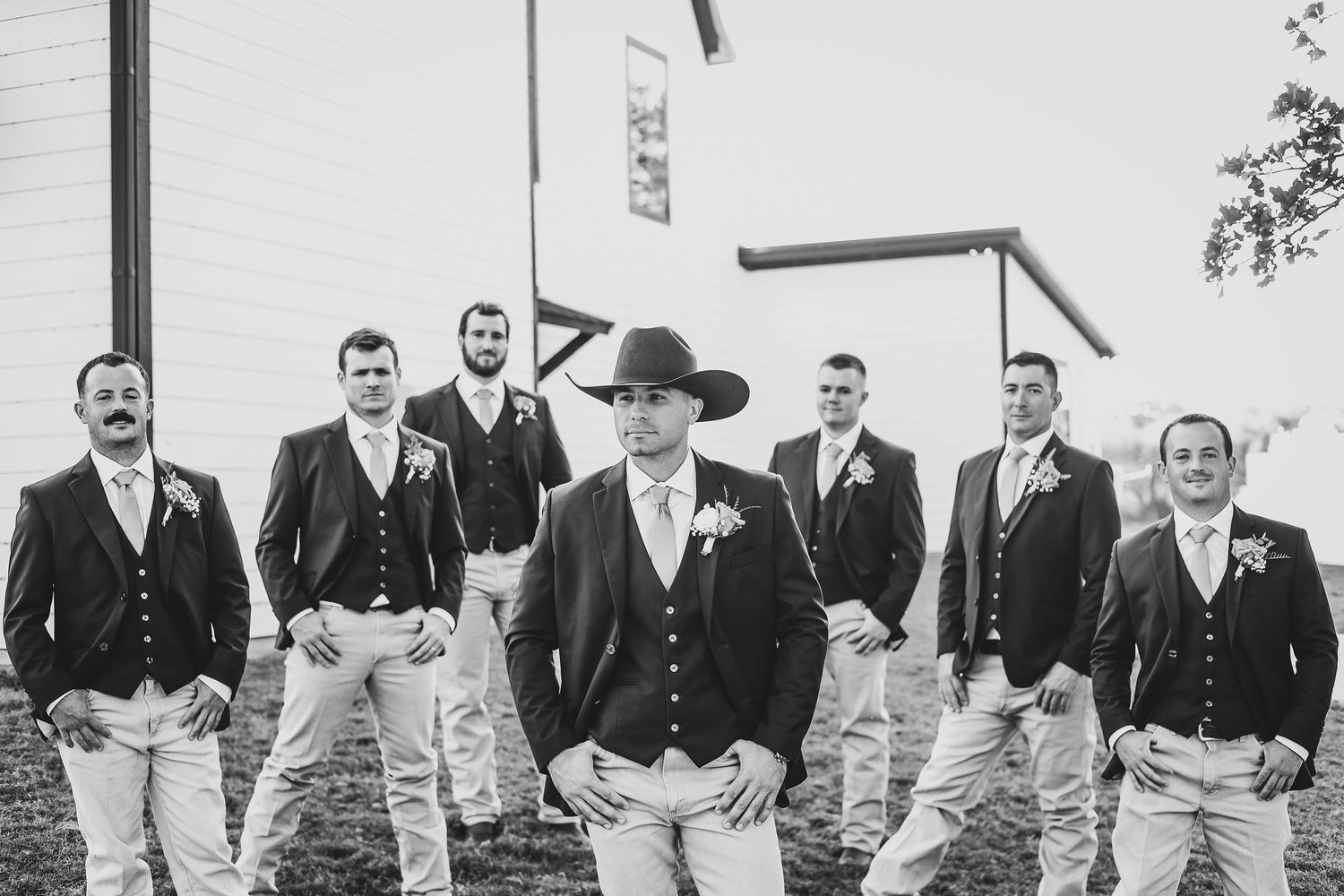 Groomsmen in navy jackets and boots at barn wedding