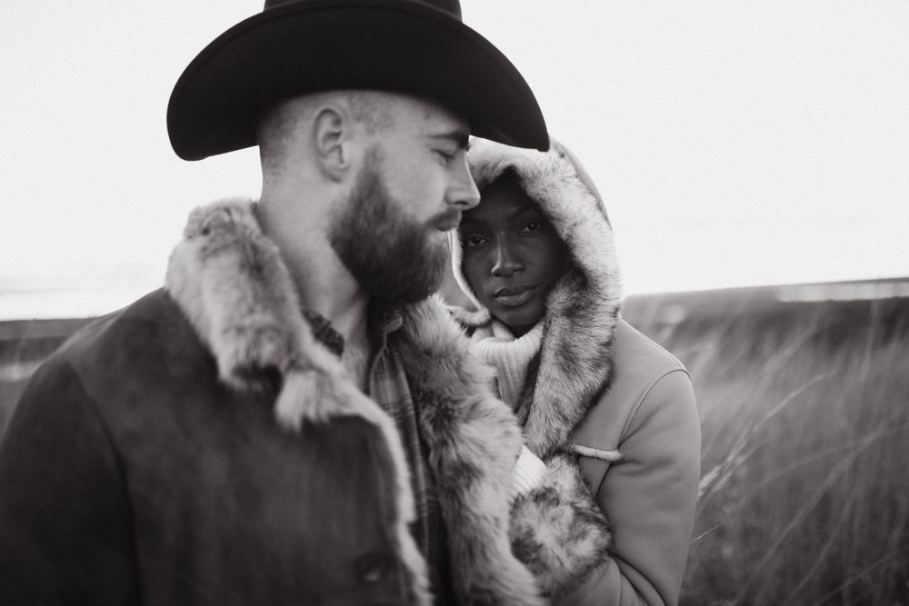 Monochromatic portrait of a bearded cowboy in traditional hat with sunlight creating atmospheric smoke effects.