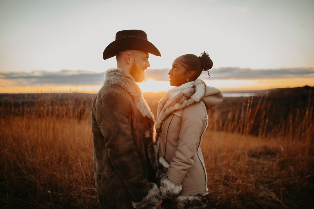 A couple embraces in a golden wheat field at sunset creating a romantic silhouette against the warm sky.