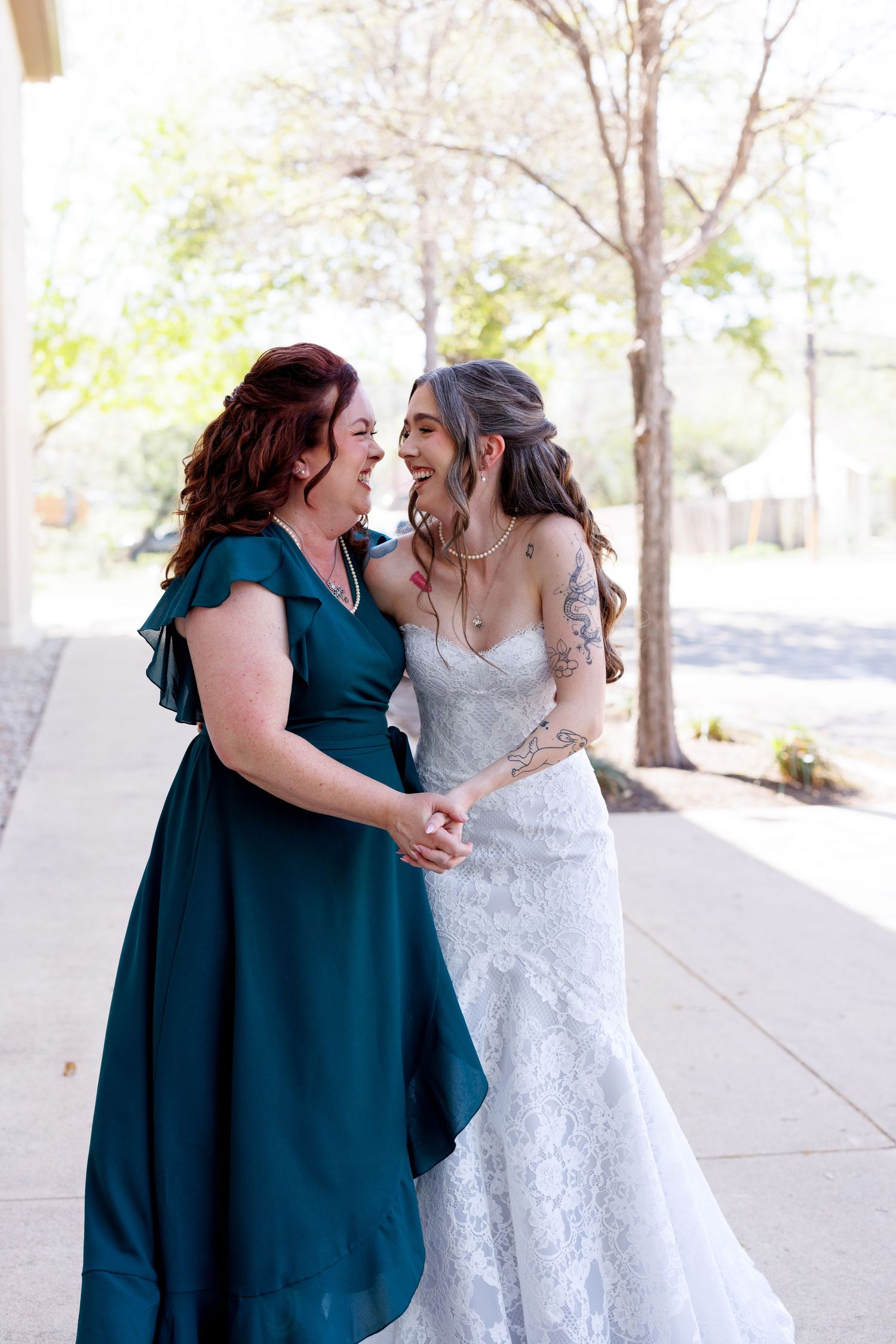 Wedding party members share a joyful moment in front of a light-colored building wall.