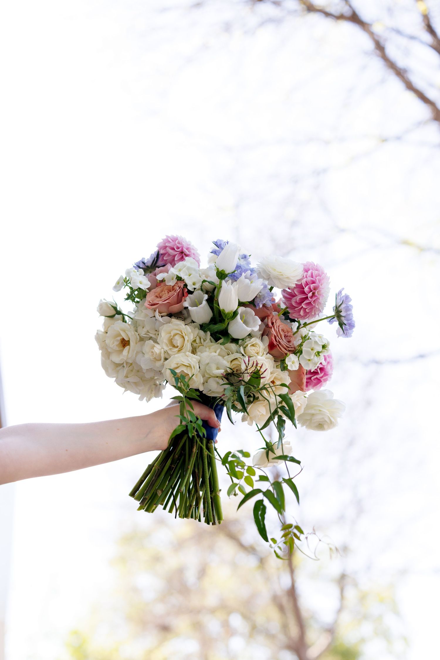 Beautiful wedding bouquet with pink and white flowers held against a bright background.