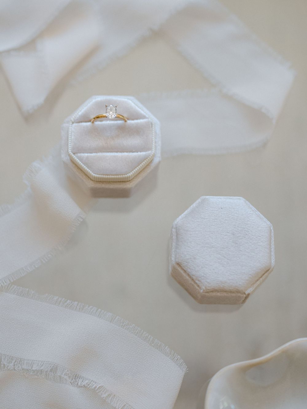 Close-up shots of delicate white hexagonal ring boxes arranged on a light fabric background.