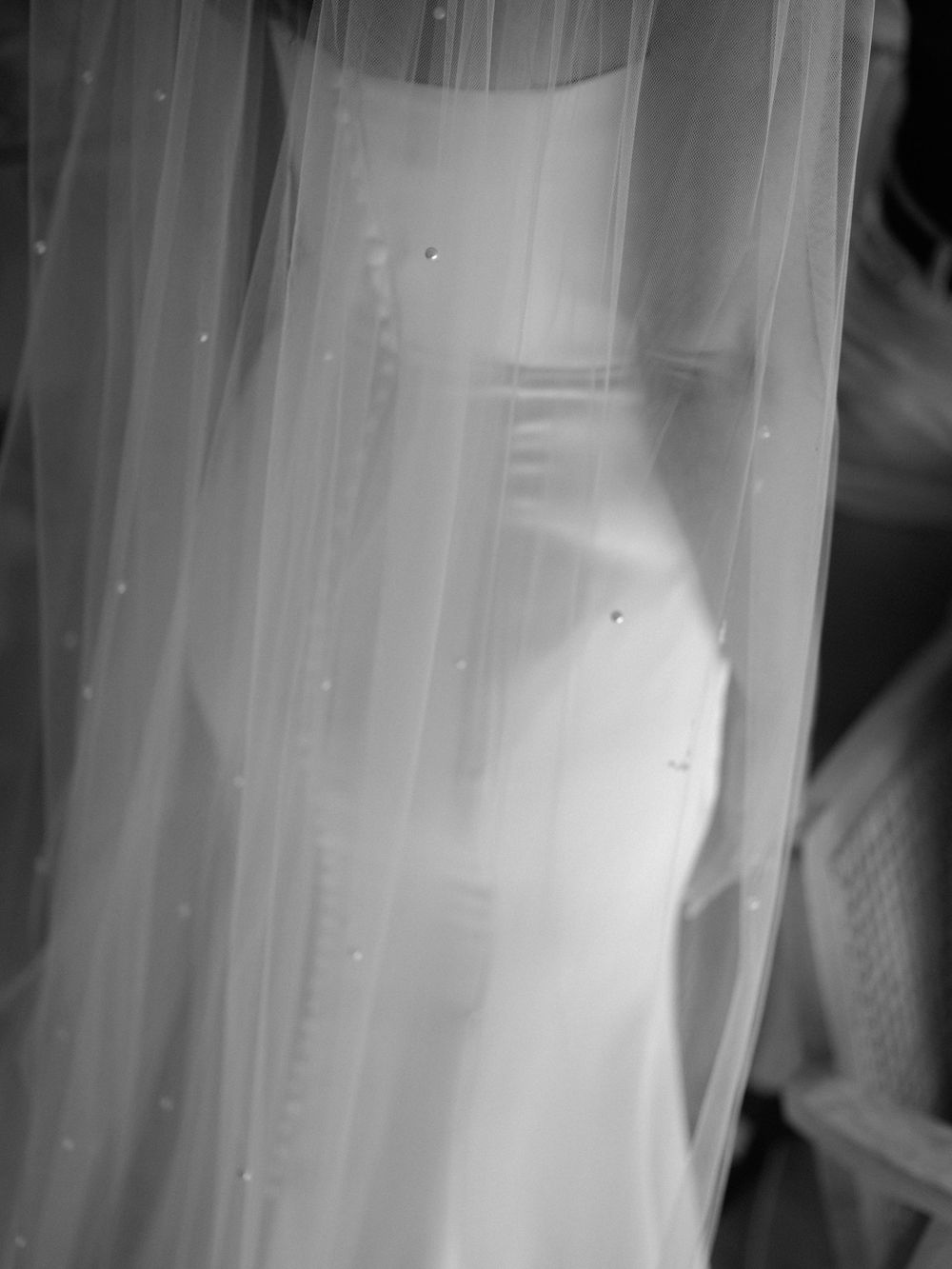 Close-up detail of a white wedding dress with flowing veil fabric creating an ethereal silhouette.