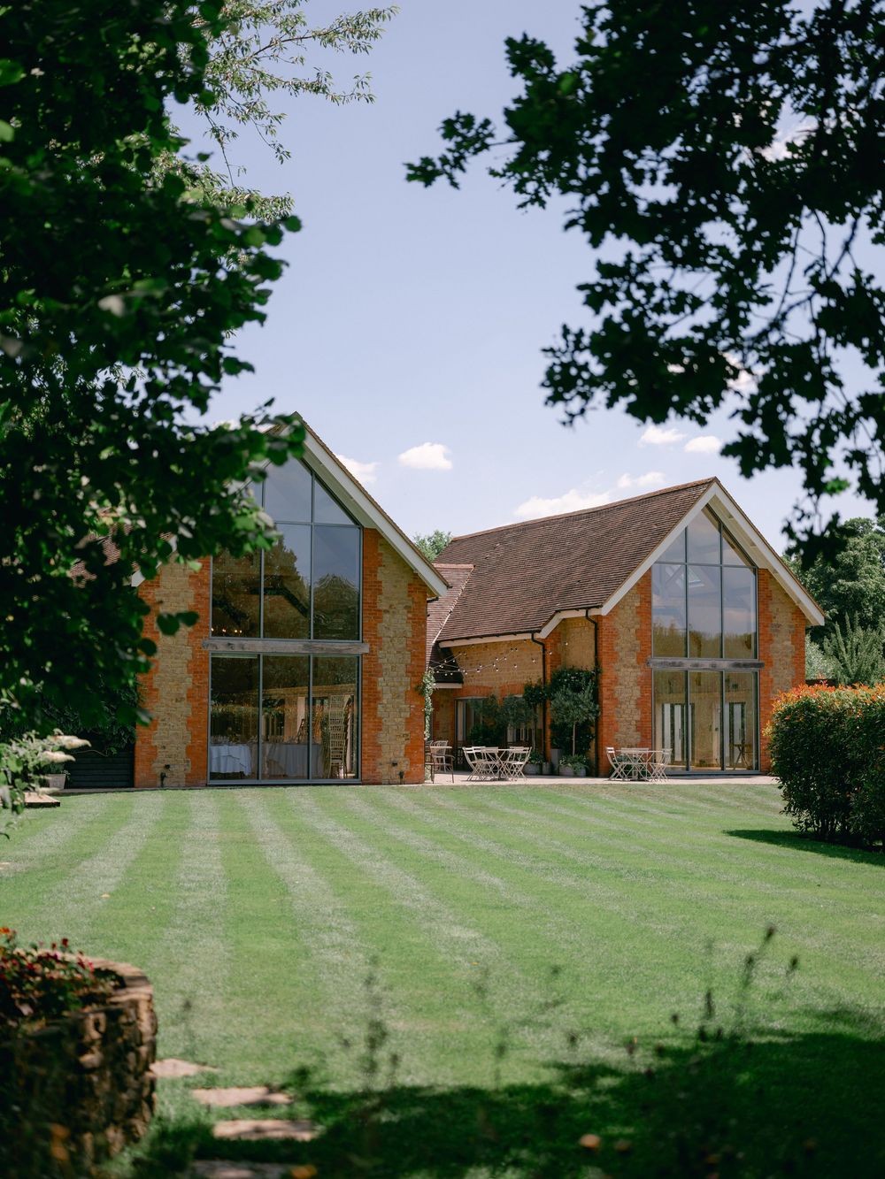 Modern brick church buildings with sloped roofs and large windows set on a grassy hillside.
