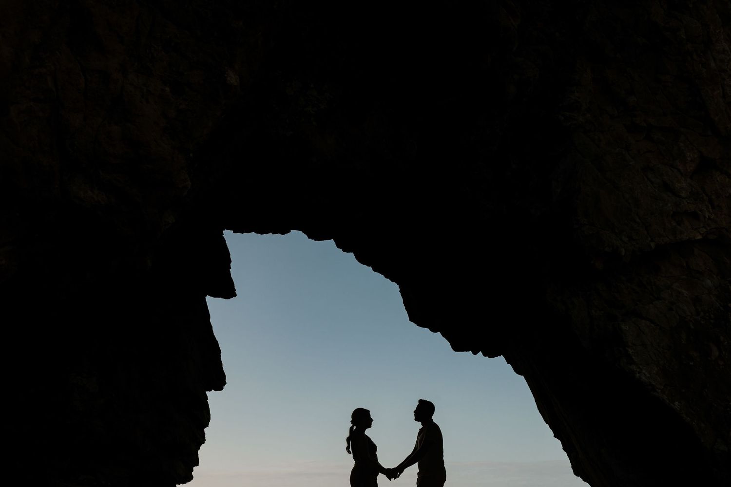 Engagement couple silhouette inside cave at Praia da Adraga, Sintra Portugal during sunset