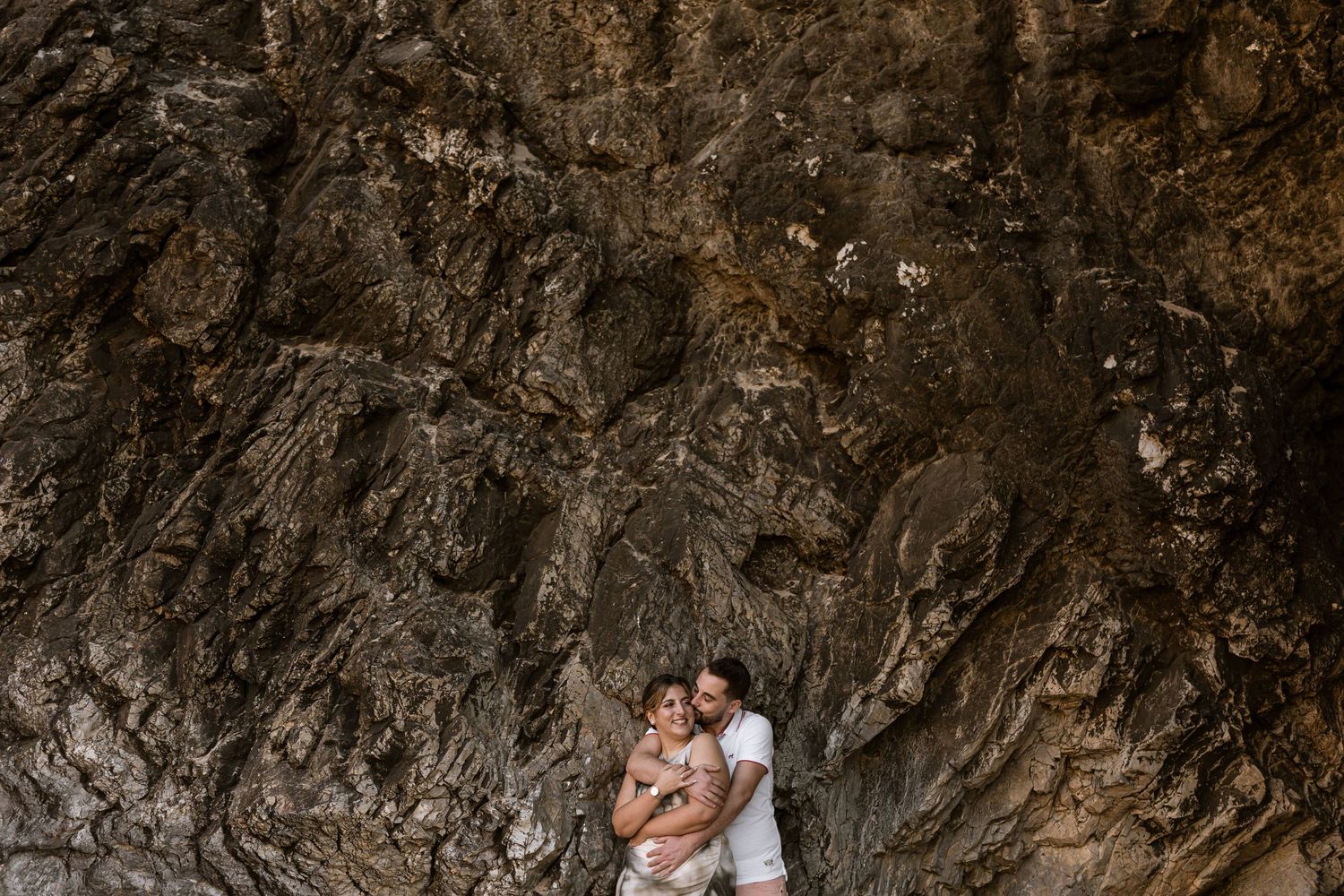 Couple embracing against dramatic cliffs at Praia da Adraga during pre wedding session in Portugal