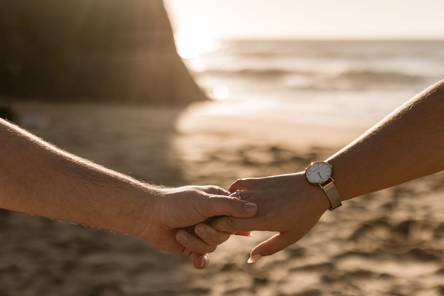 Close-up of couple holding hands with engagement ring during beach photoshoot in Sintra Portugal