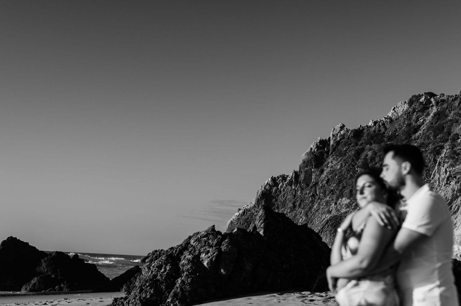 Black and white portrait of couple by the cliffs at Praia da Adraga Sintra Portugal