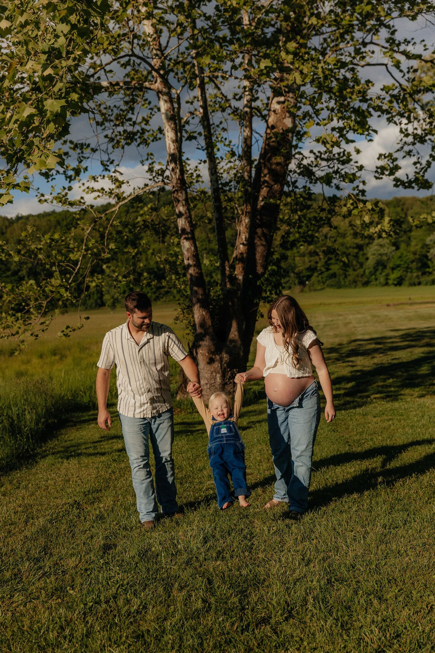 A family shares joyful moments together on an autumn day with fall foliage and a wooden fence in the background.