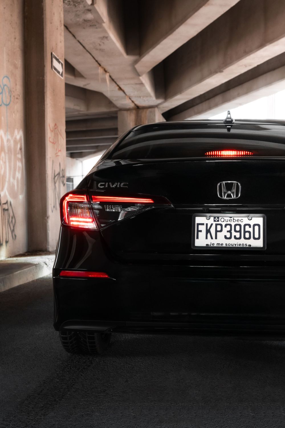 Rear view of black Honda sedan with illuminated taillights in parking garage.Mtlshutter photography