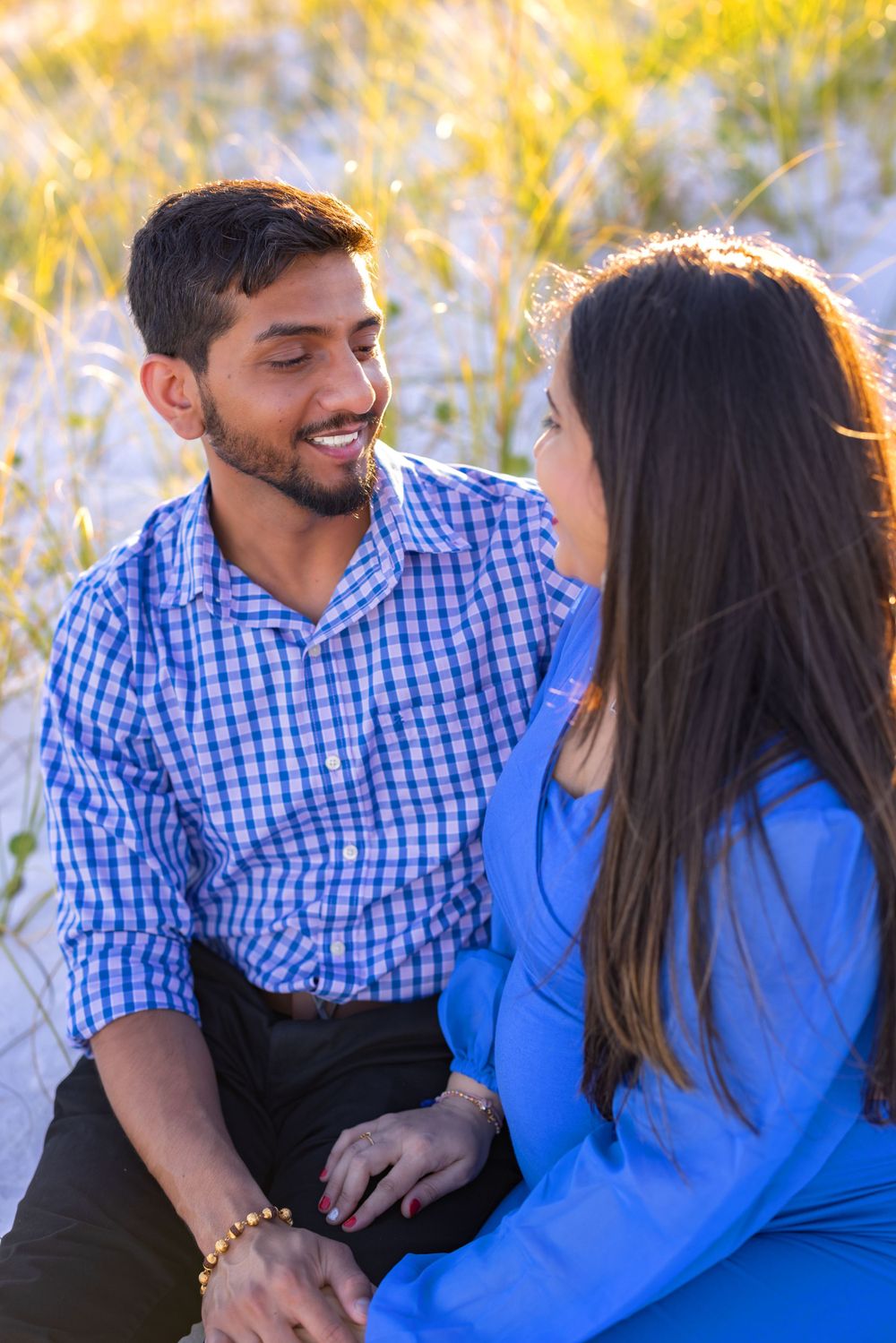 A couple in blue and plaid attire share an intimate moment outdoors with golden sunlight in the background.