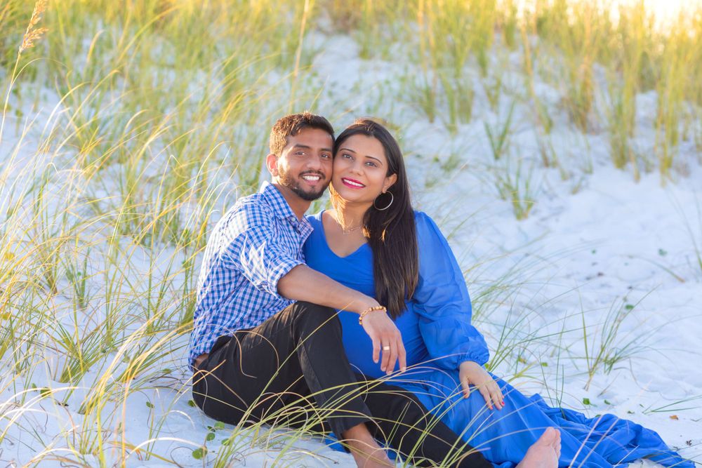 Couple sitting together on sandy dunes during golden hour.