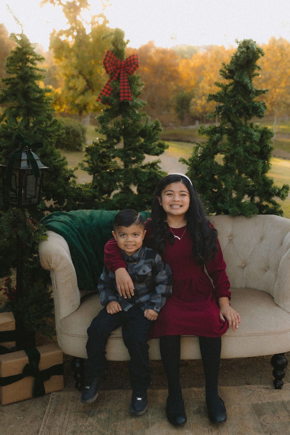 A festive holiday scene with decorative evergreen trees and a white vintage sofa outdoors during autumn.