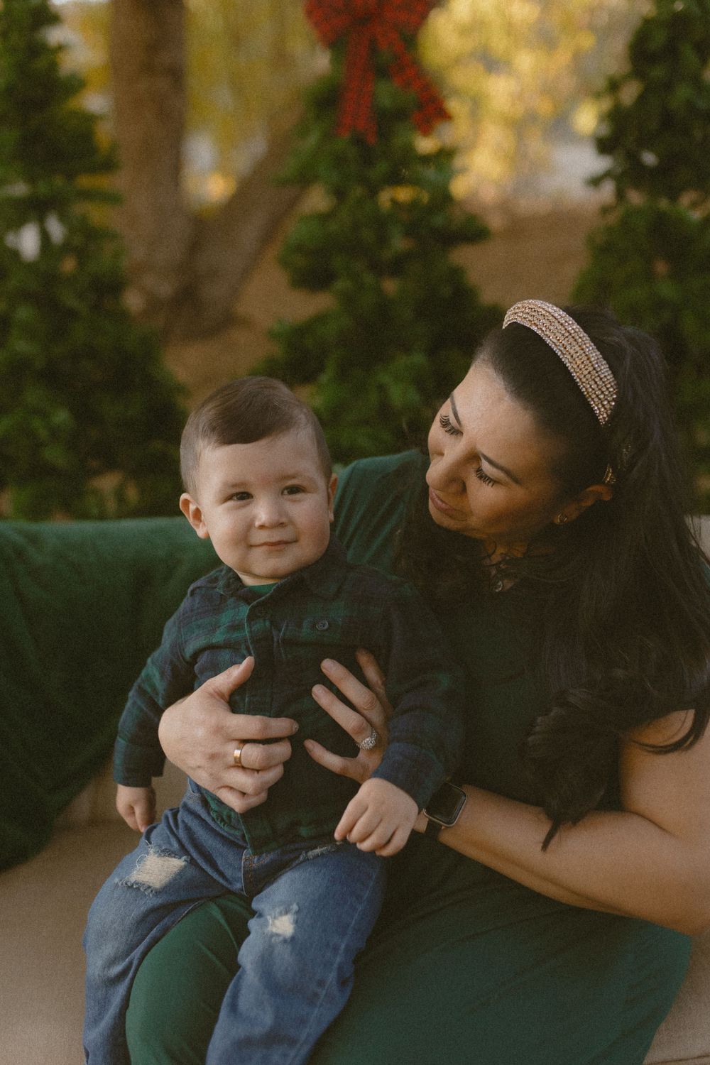 A parent and young child share a tender moment together on a green couch outdoors during golden hour.