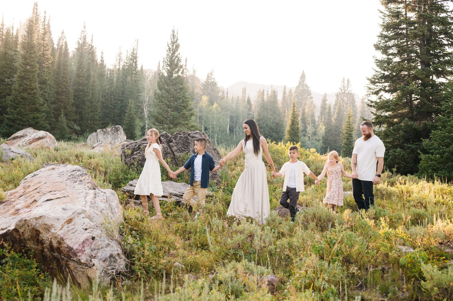 Beautiful mountain meadow photoshoot with a family in white and cream outfits at sunset.
