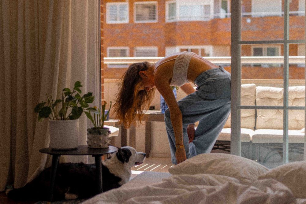 Morning stretch by window with houseplants and natural light streaming in.