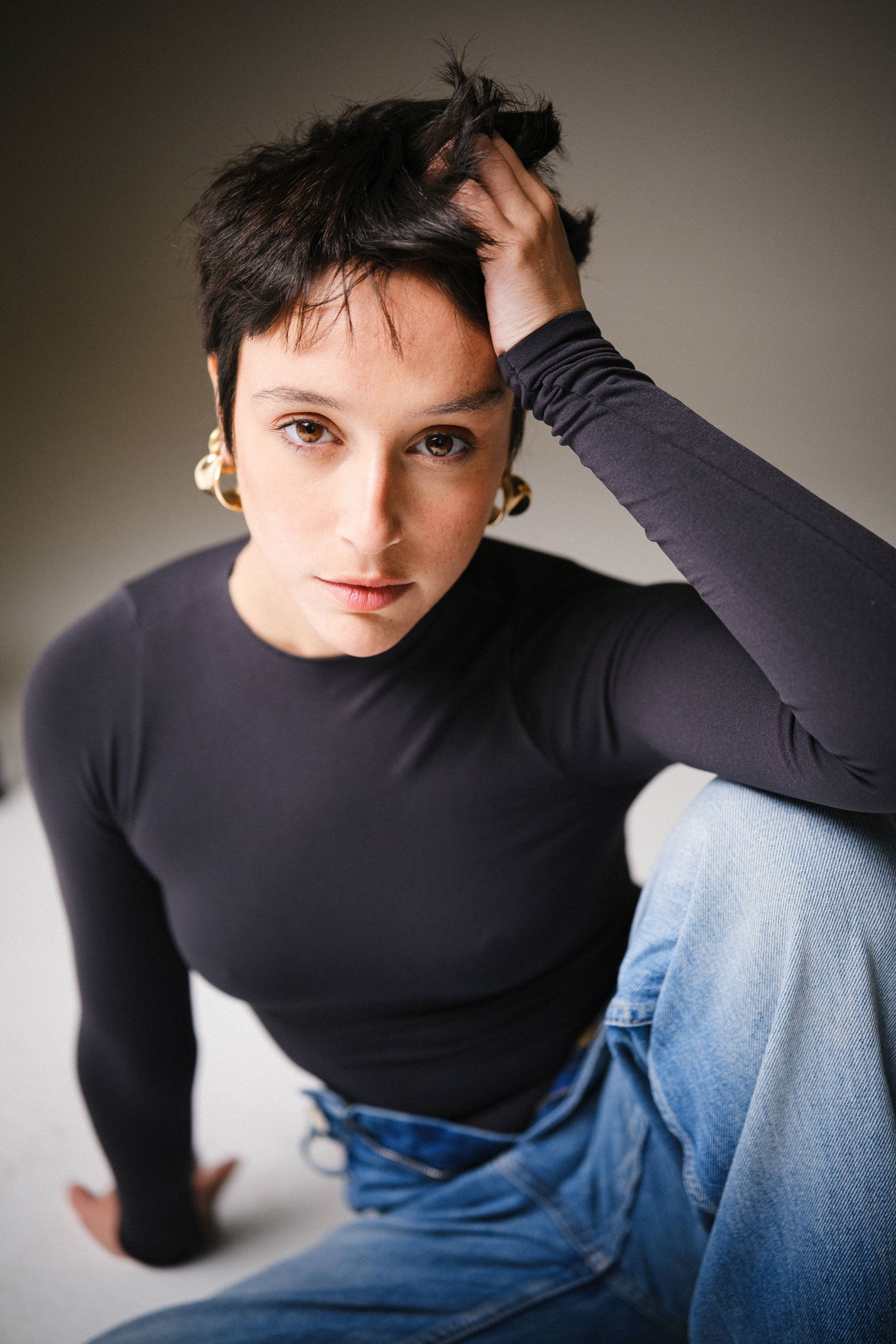 Moody portrait composition with black long sleeve top against neutral background.