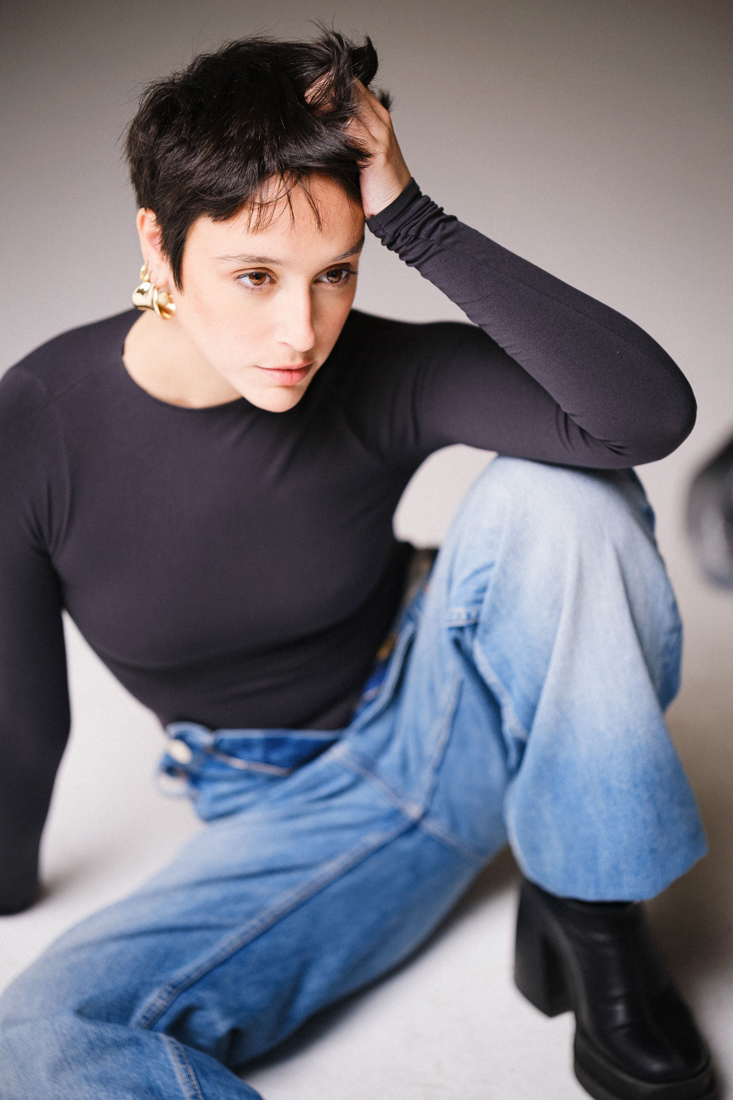 Fashion portrait featuring black turtleneck and blue jeans in a minimalist studio setting.