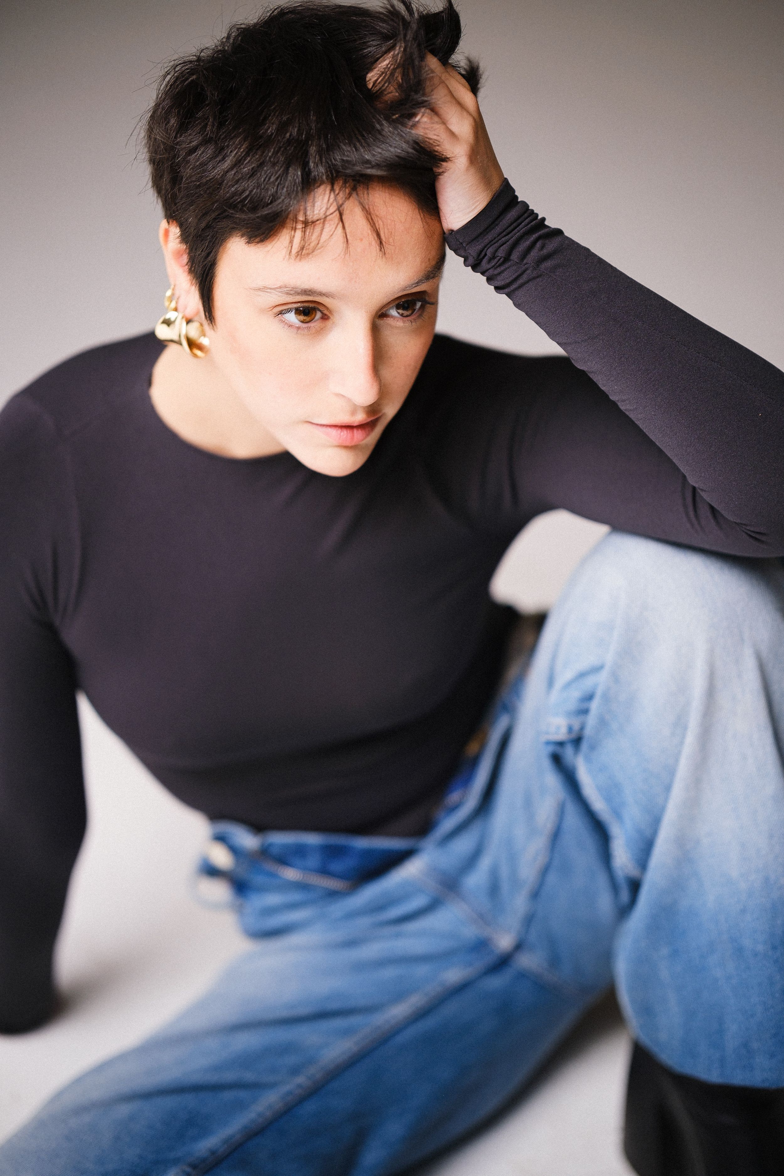 Artistic studio shot showing casual modern style with dark top and denim.