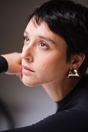 Close-up profile portrait showcasing gold earring and natural makeup.