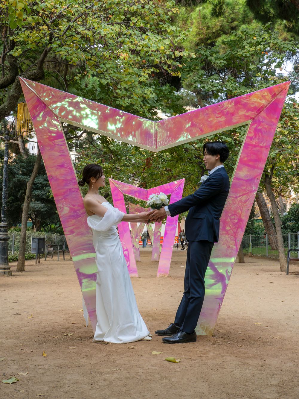 Artistic post wedding photo sequence with pink decorative banners in the park of Sagrada Familia