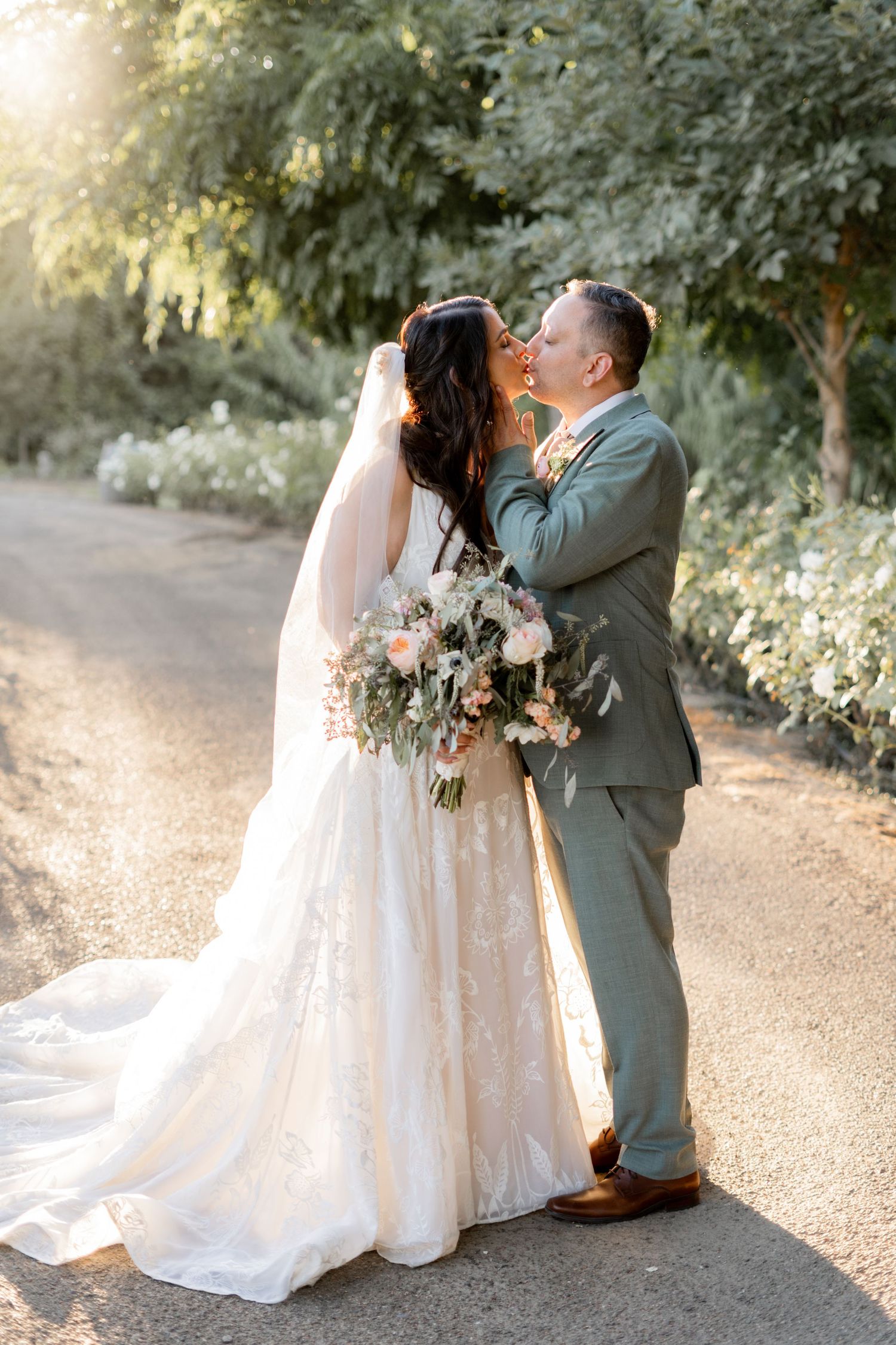 Wedding couple embracing on garden path during golden hour.