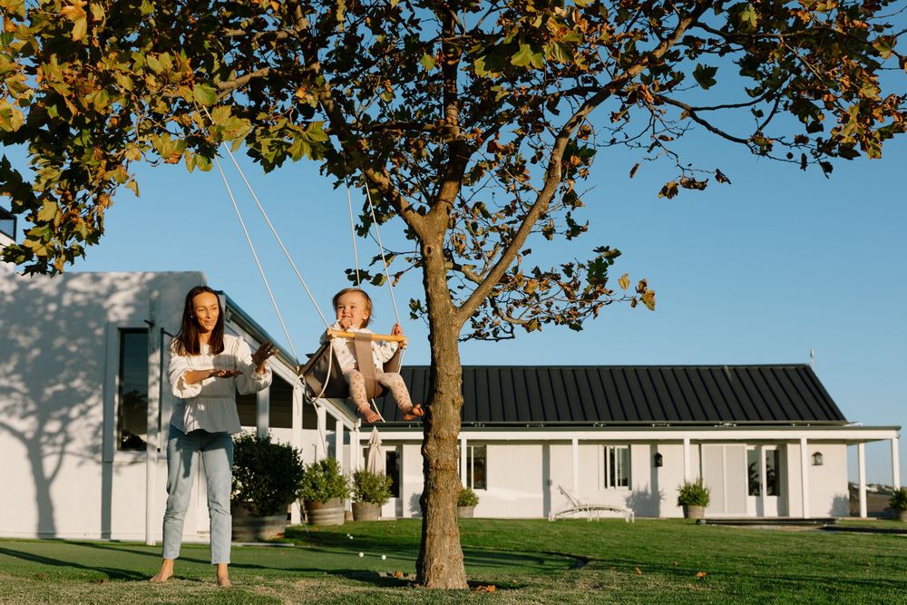 A series of outdoor family photographs taken on a sunny day with autumn trees and a white house in the background.