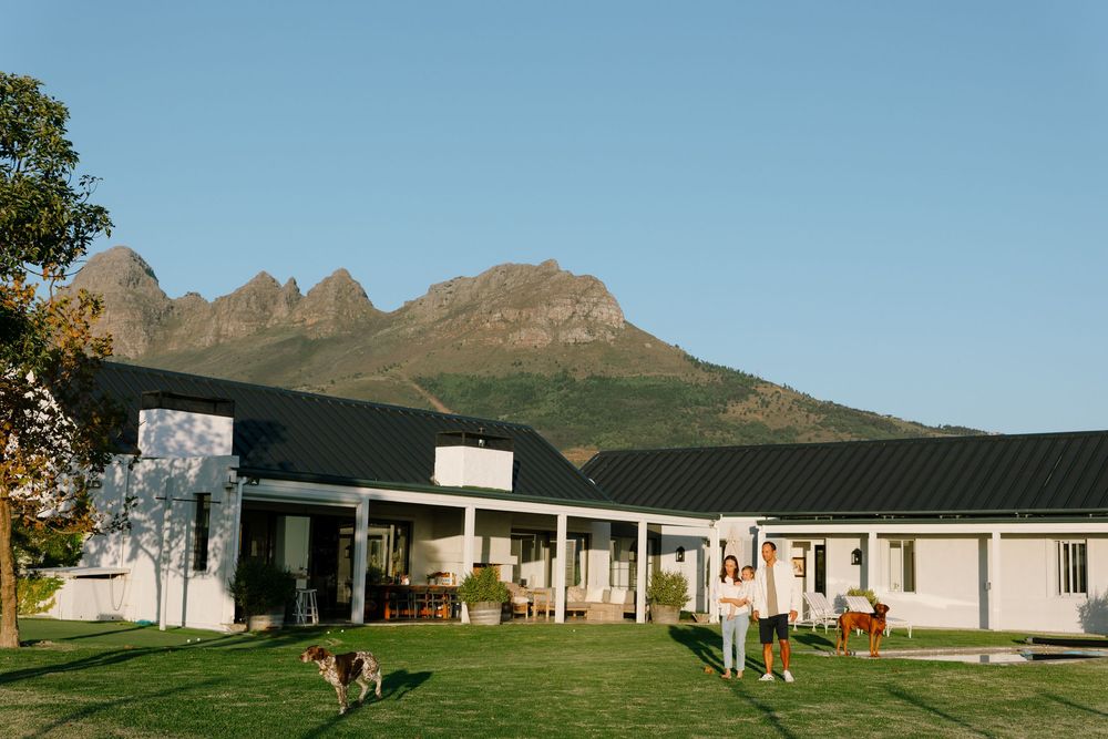 A scenic view of a property with buildings nestled in front of distant mountains and trees.