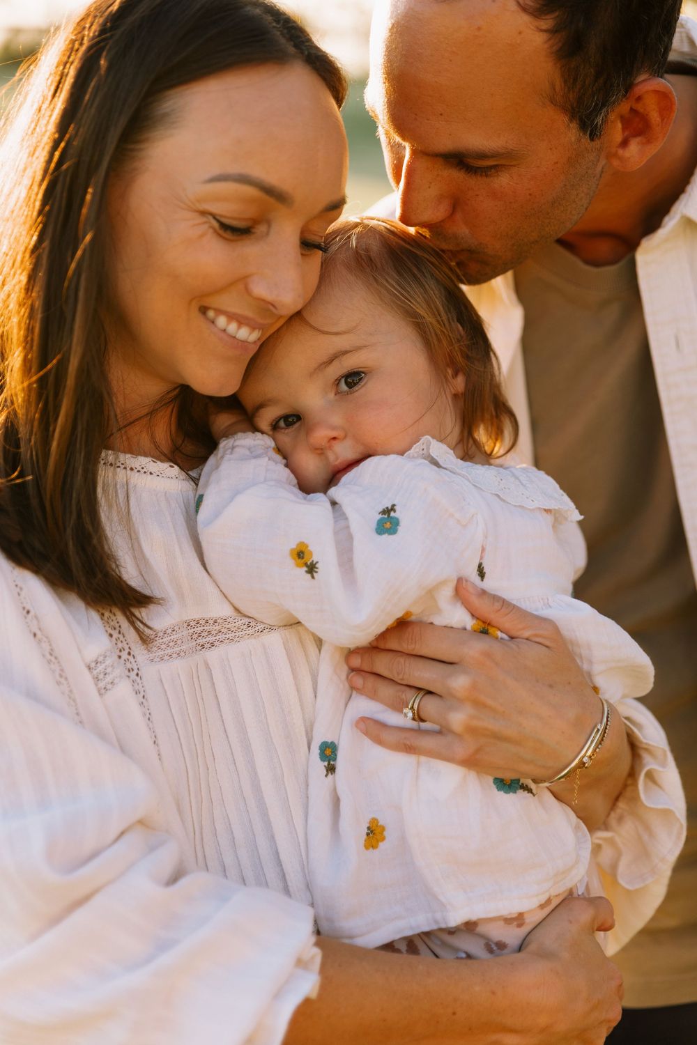 Series of intimate family moments in warm lighting with everyone wearing white.
