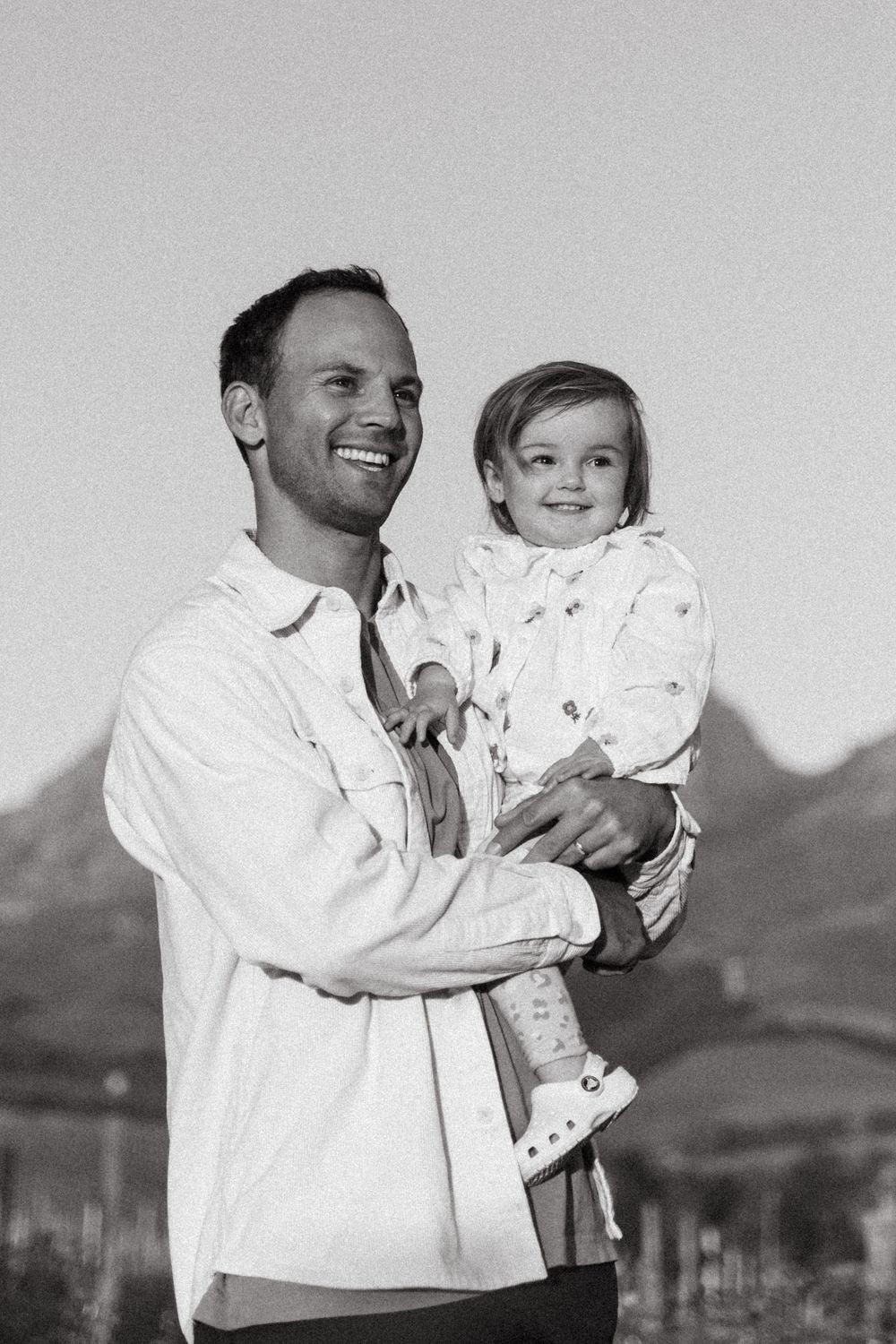 Black and white portrait series showing joyful family interactions against a plain backdrop.