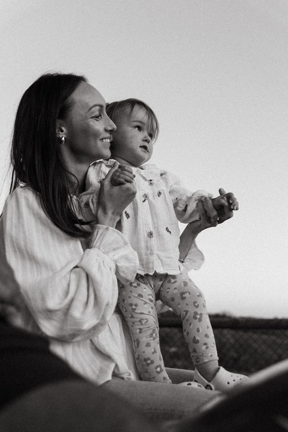 A heartwarming black and white candid moment between parent and child sitting outdoors enjoying quality time together.