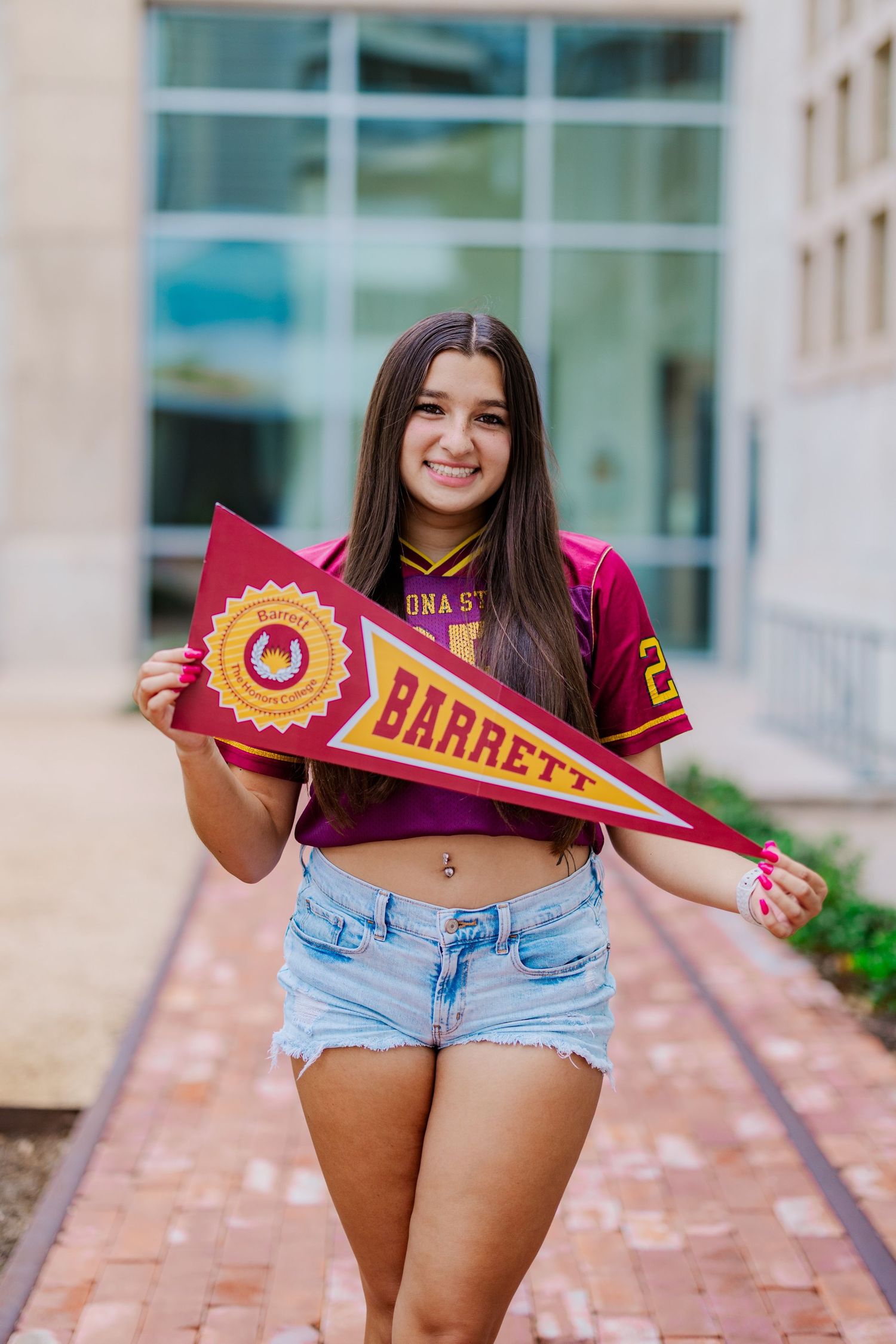 Young woman in Arizona State Barrett Honors College pennant photo wearing maroon jersey and denim shorts.