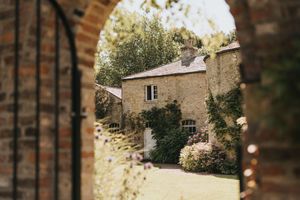 View through stone archway of a rustic cottage with climbing vines and greenery at Saltmarshe Hall - taken by Grimsby photographer.