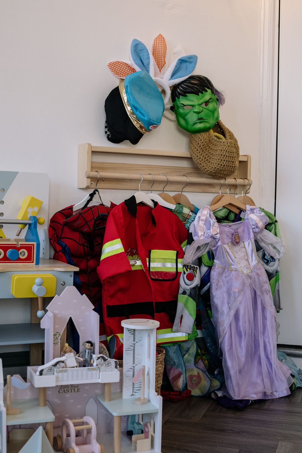 A display of children's costumes and dress-up items including a firefighter uniform, princess dress, and character masks.