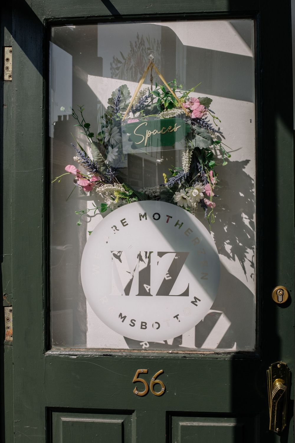 Exterior view of a modern storefront with the number 56 and decorative floral elements around the entrance.