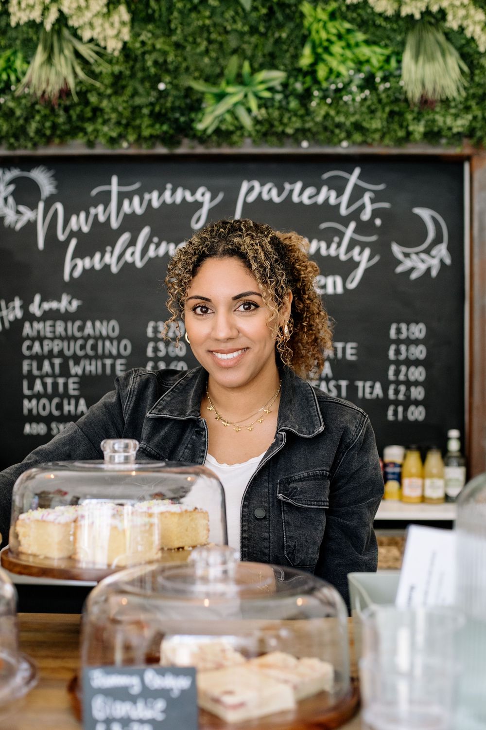 A warm and inviting cafe counter with pastry displays and a handwritten menu board featuring coffee prices.