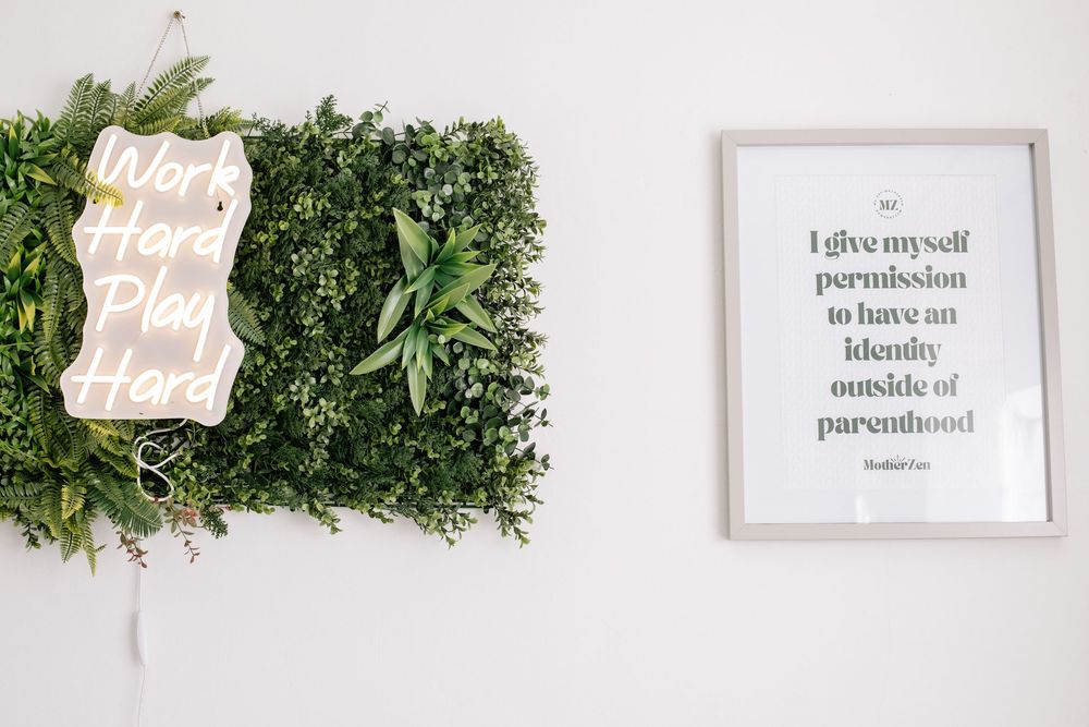 Two framed quotes on a white wall with green foliage accent decor.