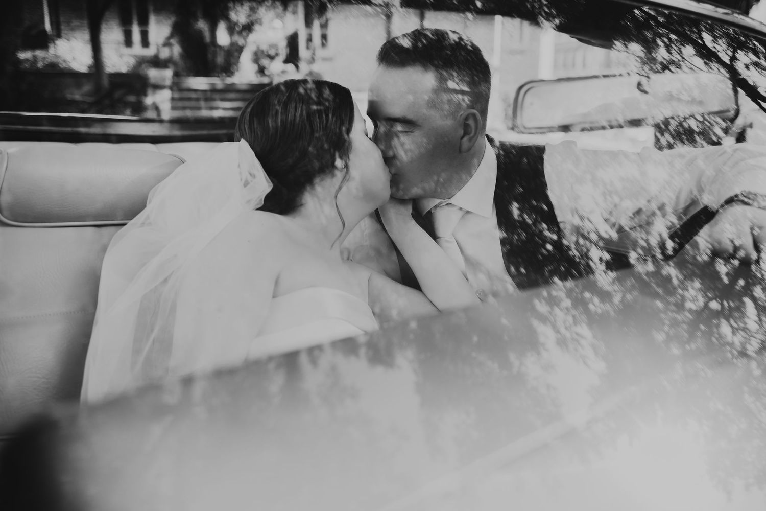 Vintage black and white photograph of a romantic couple sharing an intimate moment in a car.