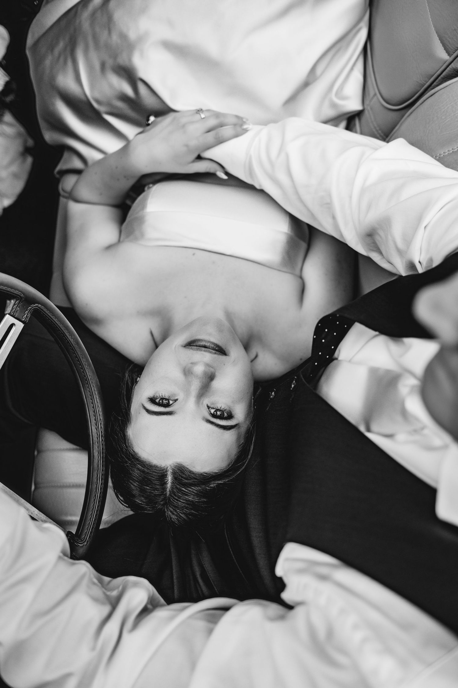 A black and white artistic portrait photo of someone lying down with white fabric and a dramatic expression.