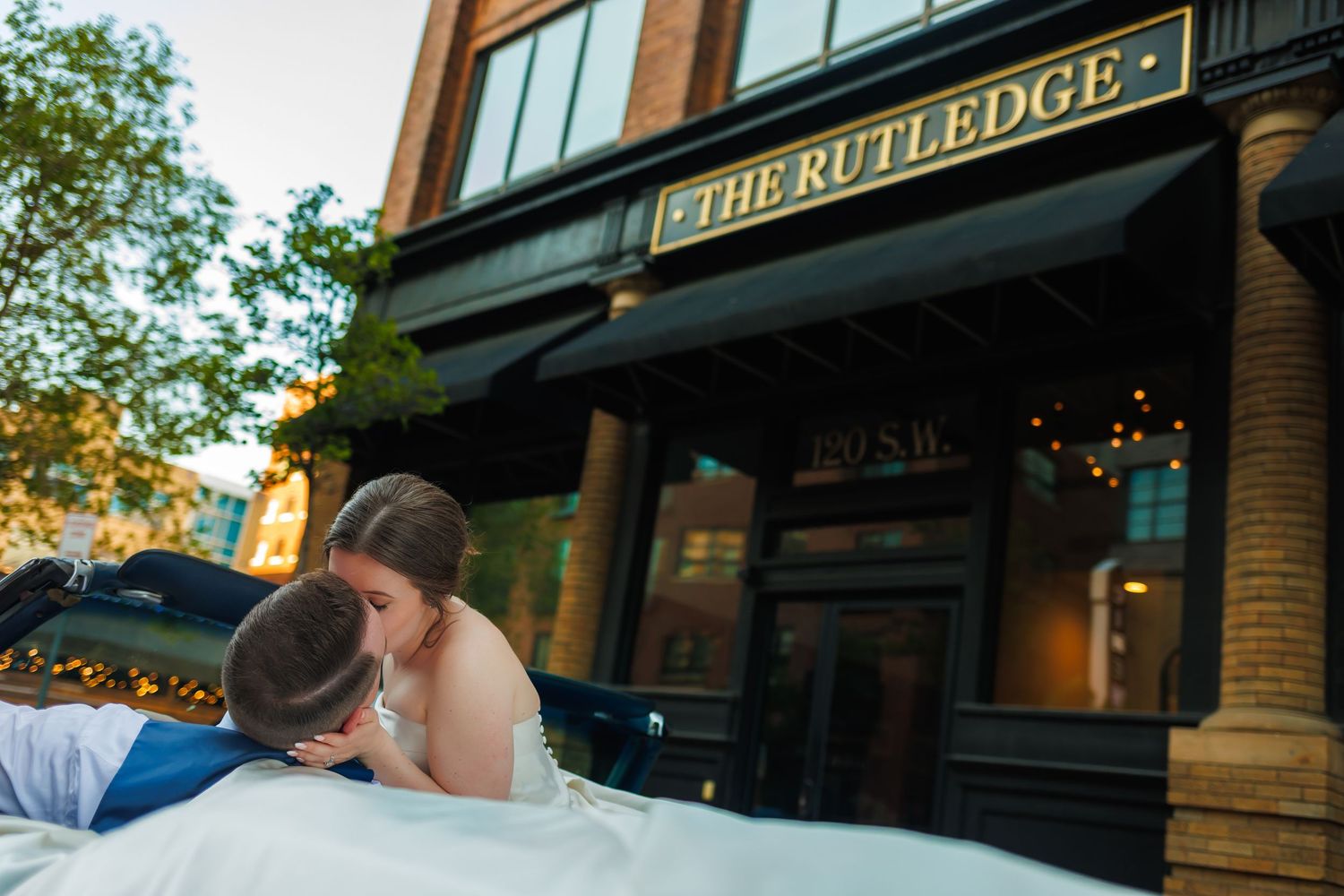 Two people share an intimate moment outside The Rutledge at twilight.