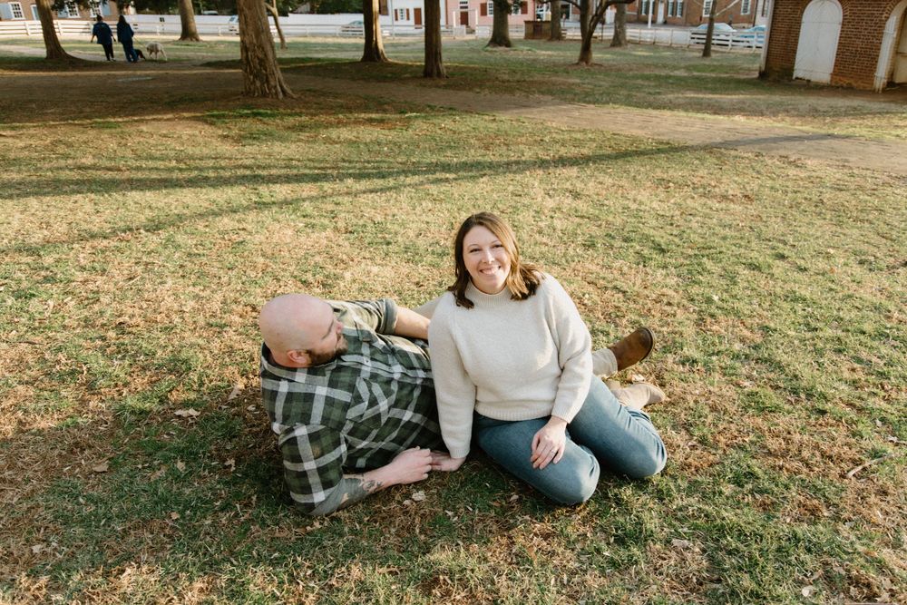Loving couple lounging together on grassy lawn during outdoor autumn photo session.